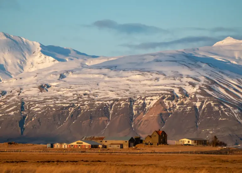 ein Bauernhof vor einer Berglandschaft zur goldenen Stunde auf Island