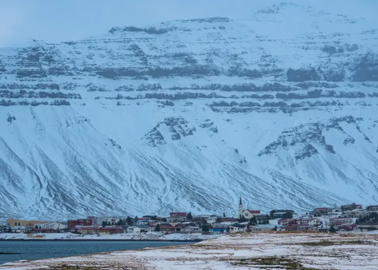 Stadt auf Island vor einem großen Berg aus der Ferne fotografiert